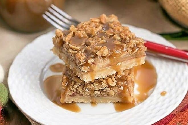 Caramel Apple Streusel Bars stacked on a white plate and drizzled with caramel
