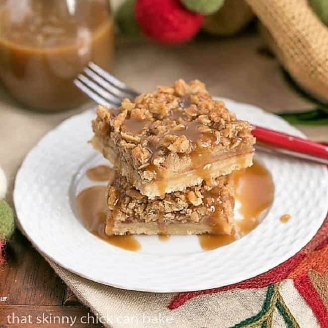 Caramel Apple Streusel Bars stacked on a white plate and drizzled with caramel.
