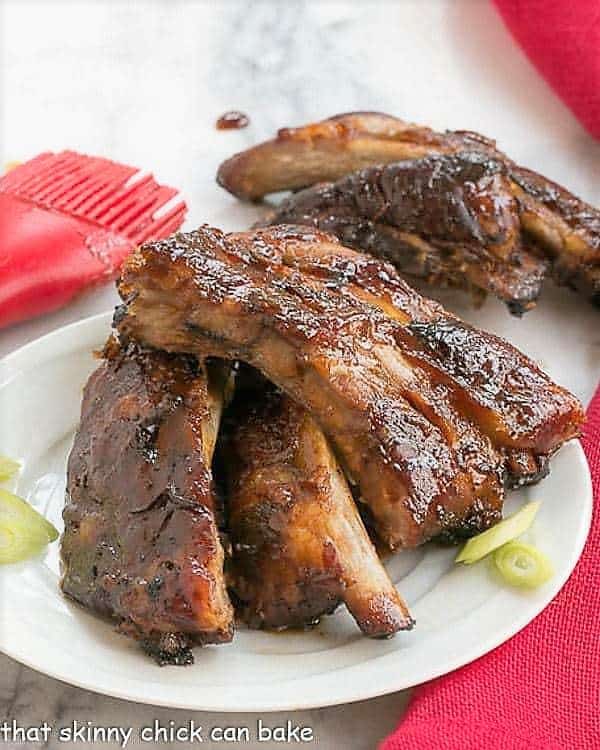 Asian Baby Back Ribs on a small white plate with some thin scallion slices.