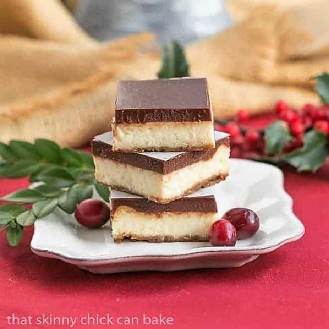 Ganache Topped Cheesecake Bars stacked on a square white plate.