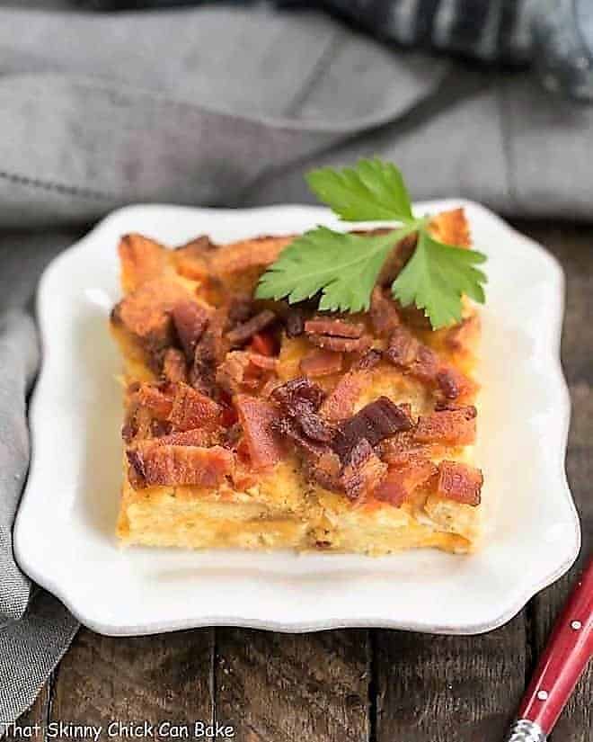 Bacon and egg strata slice on a small white plate.