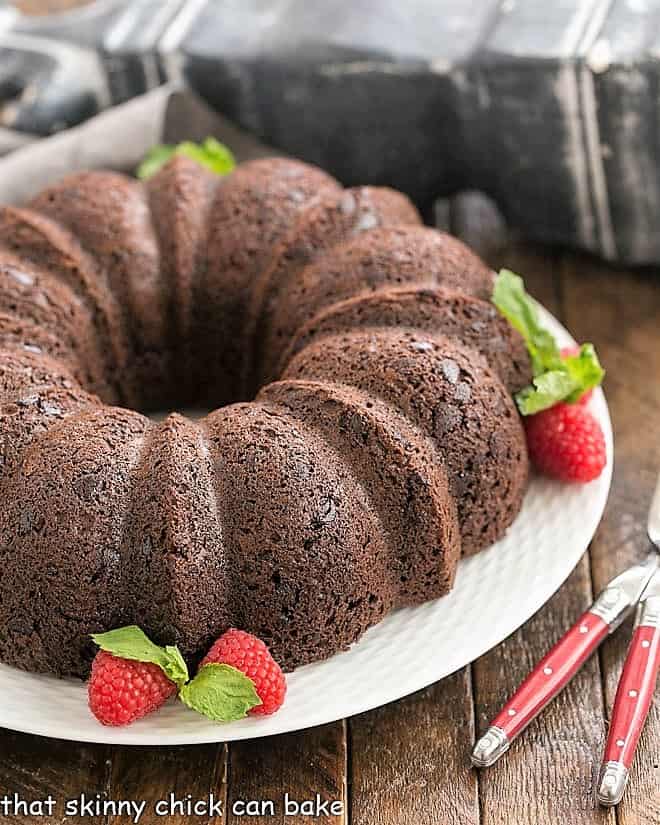 Chocolate Kahlua Bundt Cake - Made easy with a cake mix, but tastes like it was made from scratch. Rich, dense and loaded with chocolate flavor! Chocolate Bundt Cake on a white plate garnished with berries and mint.