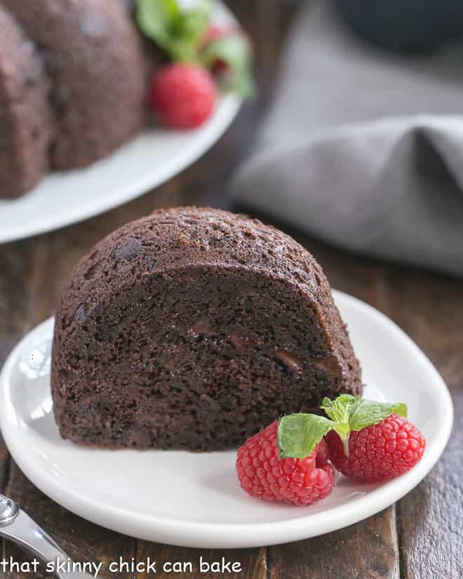 Chocolate Kahlua Cake - Made easy with a cake mix, but tastes like it was made from scratch. Rich, dense and loaded with chocolate flavor! Slice of Chocolate Kahlua Cake with whole cake in the background.