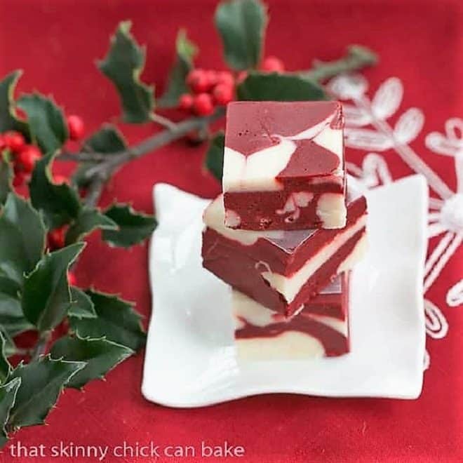 Stack of red velvet fudge on a small white plate with holly berries