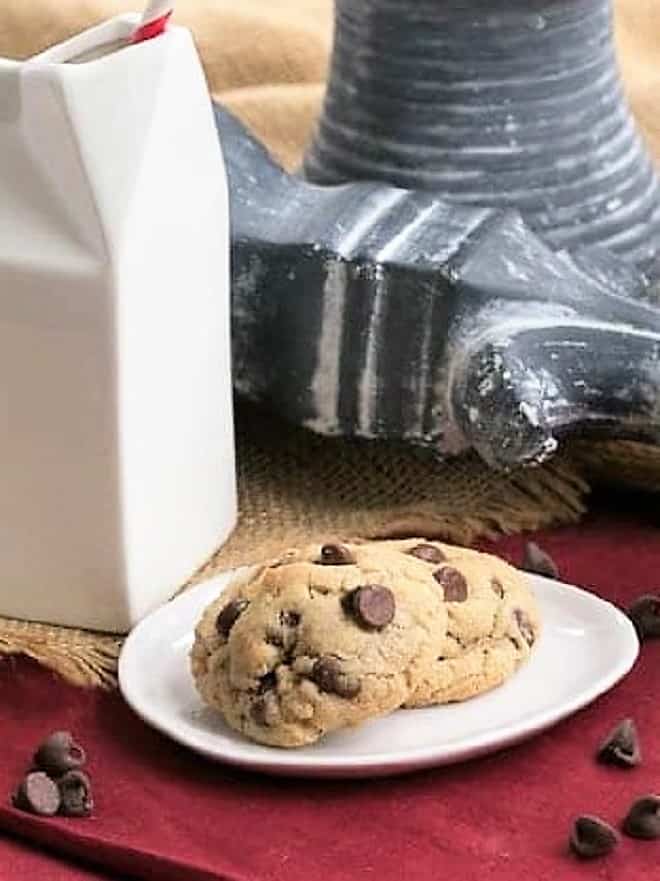 Rum Spiked Chocolate Chip Cookies on a white plate next to a ceramic carton of milk