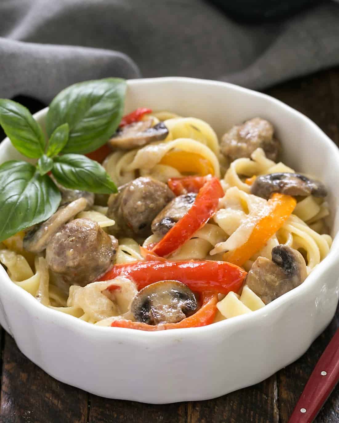 Sausage, Pepper, Mushroom Fettuccine in a white bowl with a red handle fork.