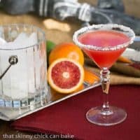 Blood Orange Margaritas in stemmed cocktail glass in front of oranges and a crystal ice bucket