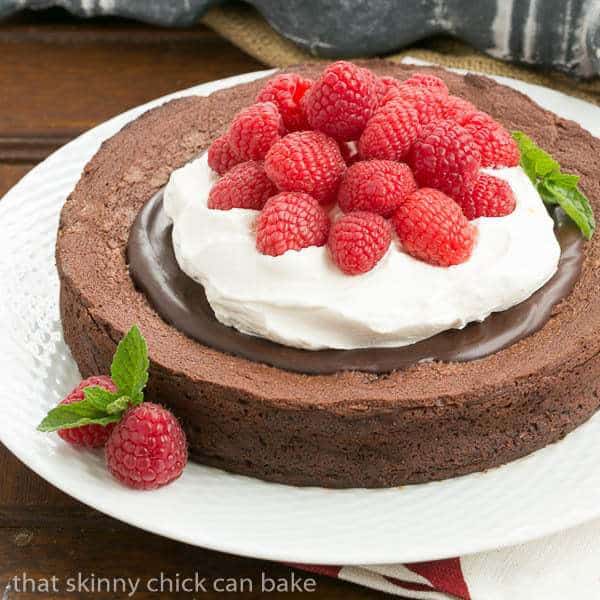 Chocolate Earthquake Cake on a white plate topped with chocolate, cream and berries.