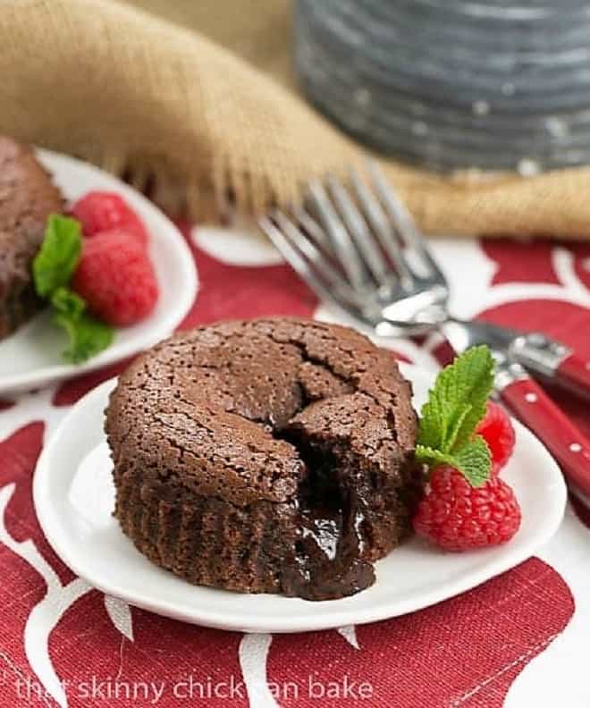 Chocolate Lava Cakes broken open with the fudgy centers exposed on a white dessert plate.