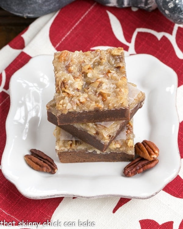 German Chocolate Brownies on a square white plate with pecan halves.