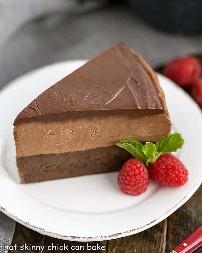 Frozen Chocolate Mousse Cake on a white dessert plate with fresh raspberries and mint.