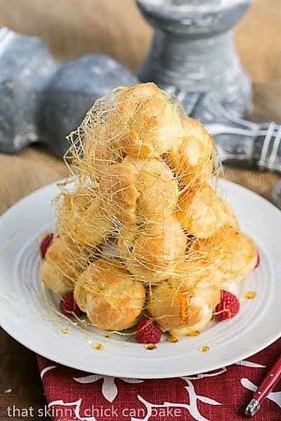 Lemon Cream Croquembouche wrapped in spun sugar on a white serving plate.