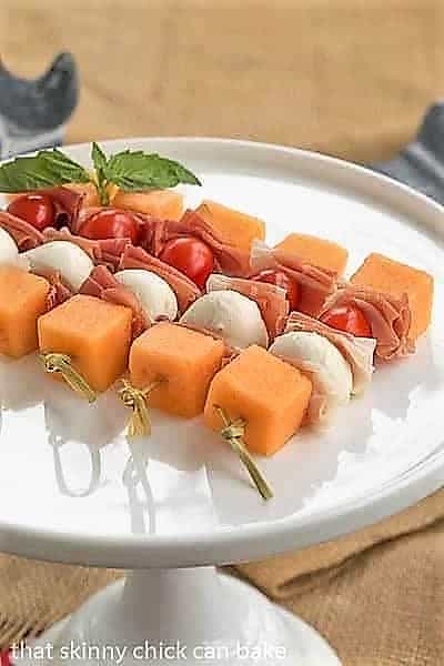 Melon and Prosciutto Skewers on a white ceramic cake stand