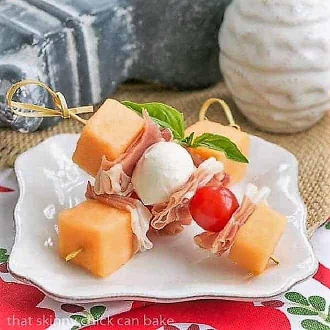 Melon and Prosciutto Skewers on a small white appetizer plate.