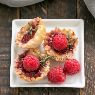 OVerhead view of a baked brie appetizer with raspberries and rosemary