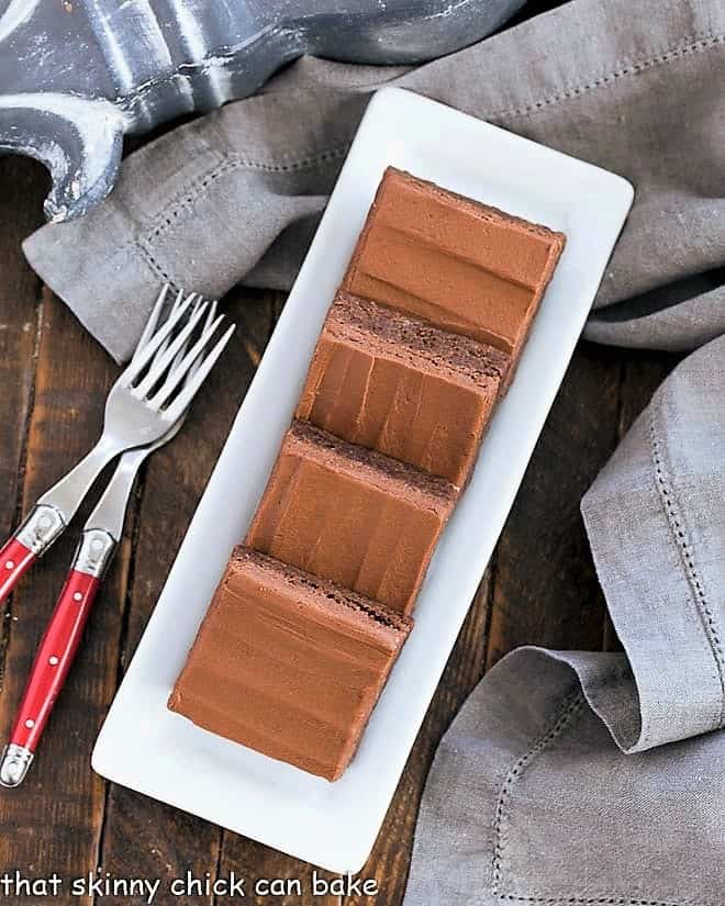 Overhead view of frosted brownies lined up on a narrow white tray