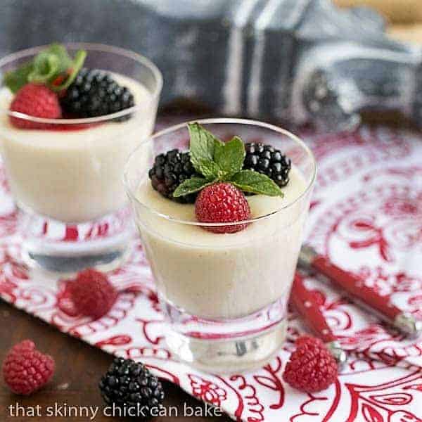 2 servings Vanilla Bean Panna Cotta garnished with berries and mint.
