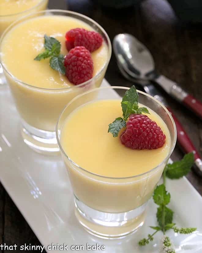 Overhead view of 2 glasses filled with white chocolate pudding with frangelico topped with berries and mint.