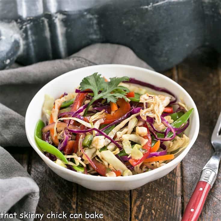 A small white bowl of Asian salad with a red handle fork