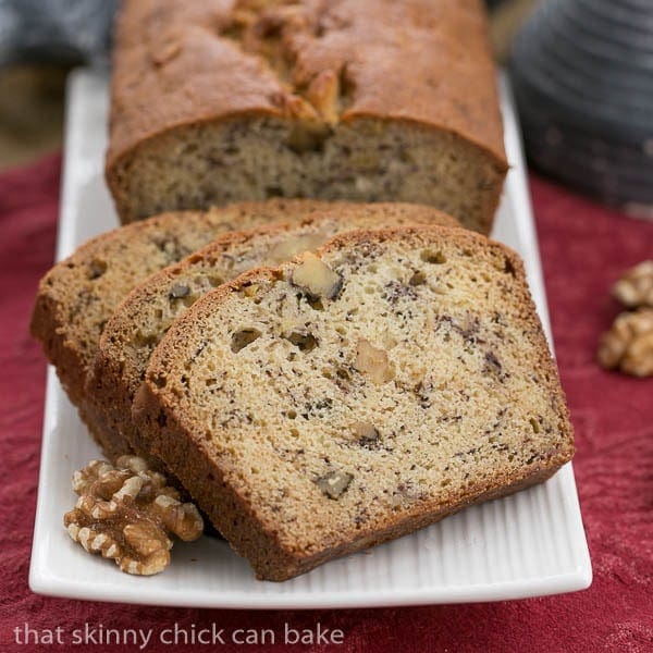 A loaf of banana nut bread and slices on a white tray