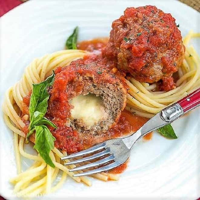 Mozzarella Stuffed Meatballs intertwined with spaghetti and garnished with basil.