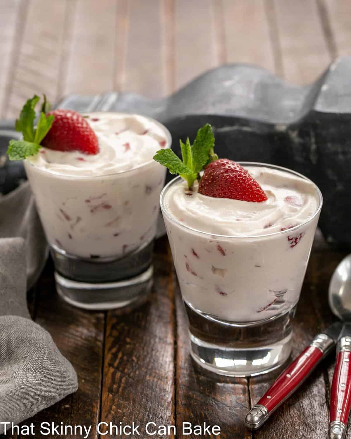 2 dishes of strawberry fool garnished with a half strawberry and mint sprig.