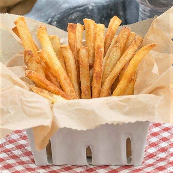 Thin Crispy French Fries in a ceramic basket lined with parchment.