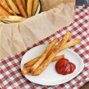 Thin Crispy French Fries on a white plate with a dollop of ketchup
