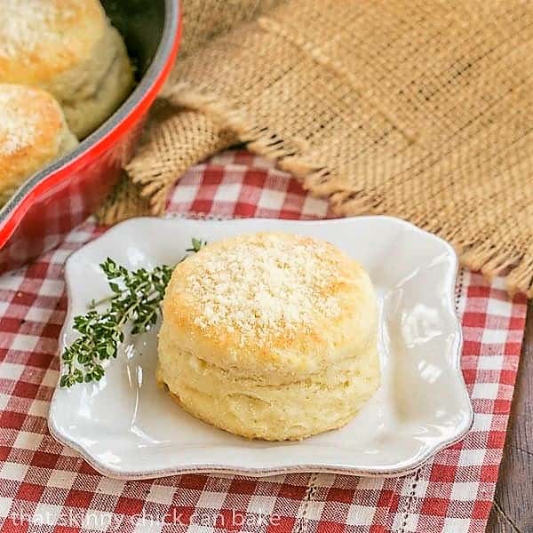 Buttermilk Goat Cheese Biscuits on a square white plate with a sprig of thyme.