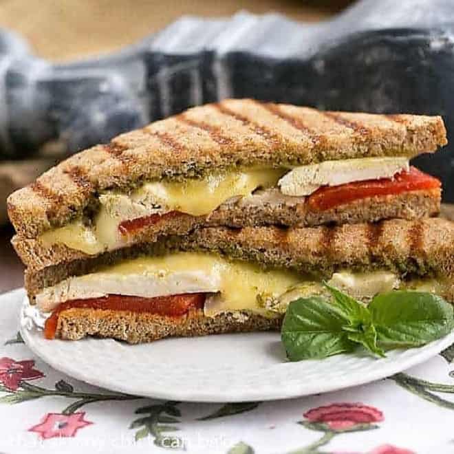 Chicken Pesto Grilled Cheese halves stacked on a white plate.