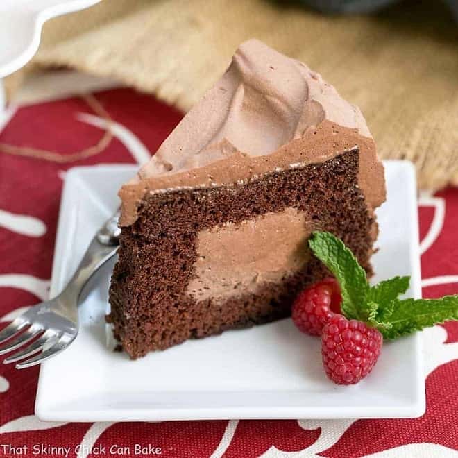 Tunnel of Mousse Cake- A fine crumb chocolate cake filled and frosting with a dreamy chocolate mousse! Tunnel of Mousse Cake slice on a square white dessert plate.