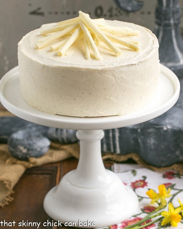 White Birthday Cake topped with white chocolate curls on a cake stand