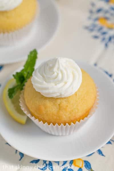 Limoncello Cupcake on a round white plate with a lemon and mint garnish.