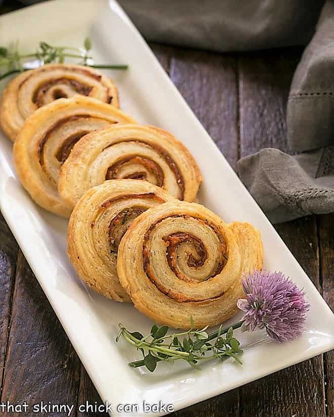 Honey Mustard Pepperoni Pinwheels on a white ceramic tray with a blossoming chive.