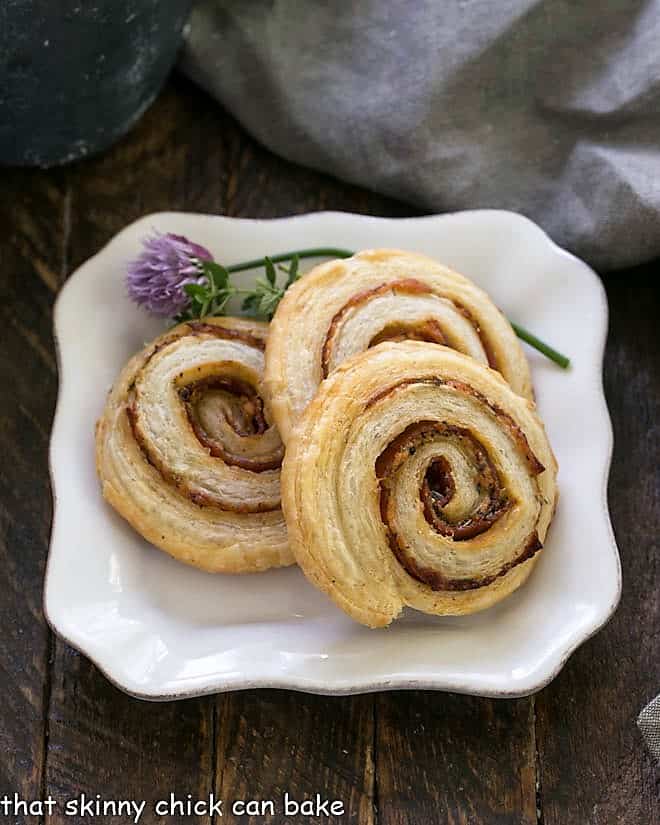 Honey Mustard Pepperoni Pinwheels on a square white plate garnished with flowering chives.