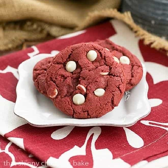 Red Velvet Cookies with White Chocolate Chips on a square white plate over a red and white napkin.