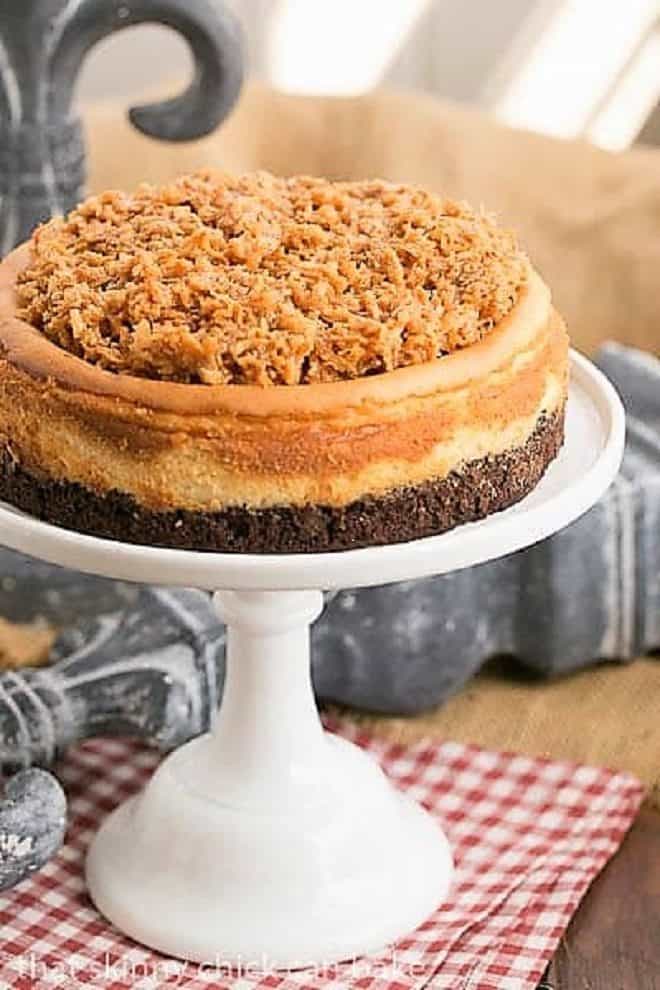 Samoa Cheesecake with a Coconut Caramel Topping on a white cake stand