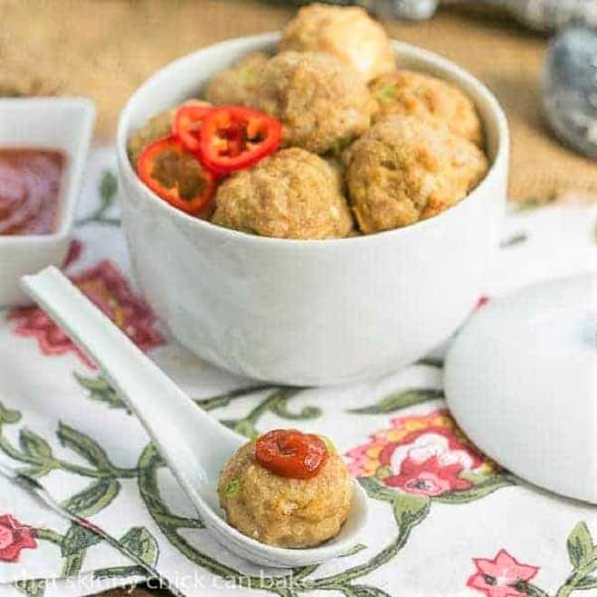 Sesame Ginger Meatballs in a white ceramic bowl with one topped with sriracha in a white ceramic spoon