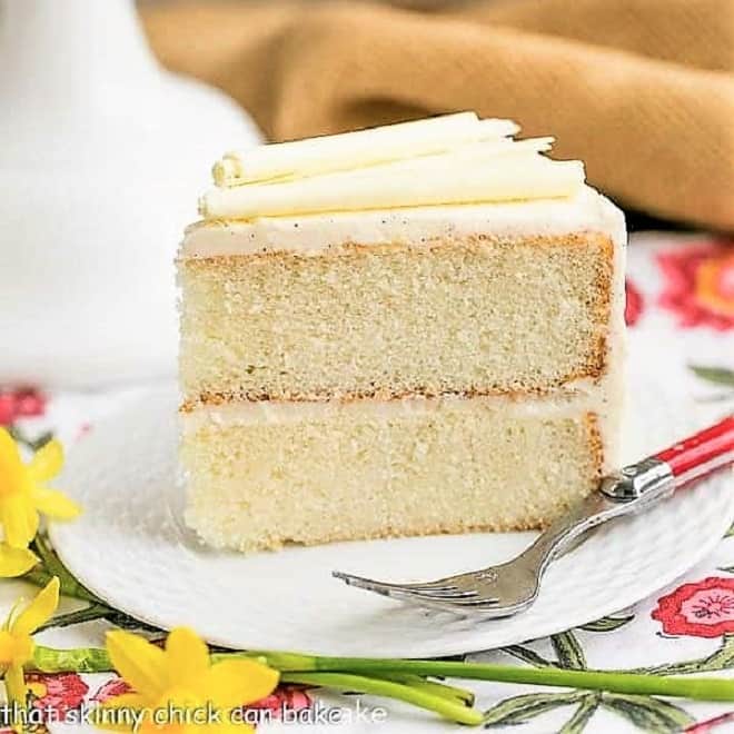 White Birthday Cake slice on a white plate with a red handle fork.