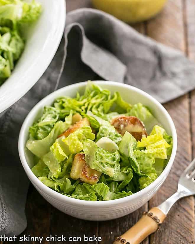 Caesar Salad Recipe in a small white salad bowl with a bamboo handled fork.