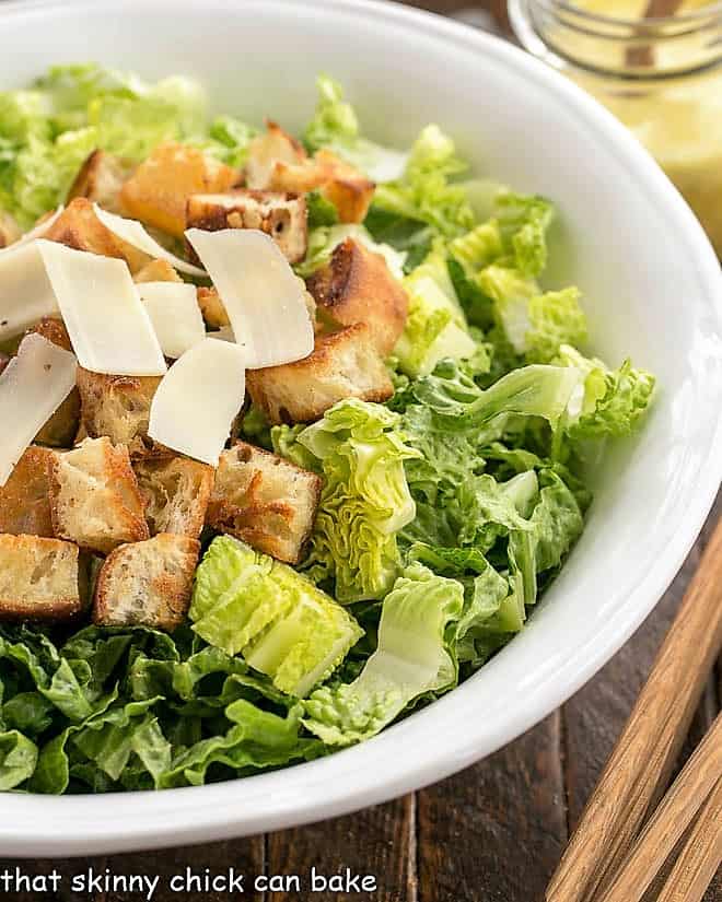 Close view of undressed Caesar salad in a white serving bowl.