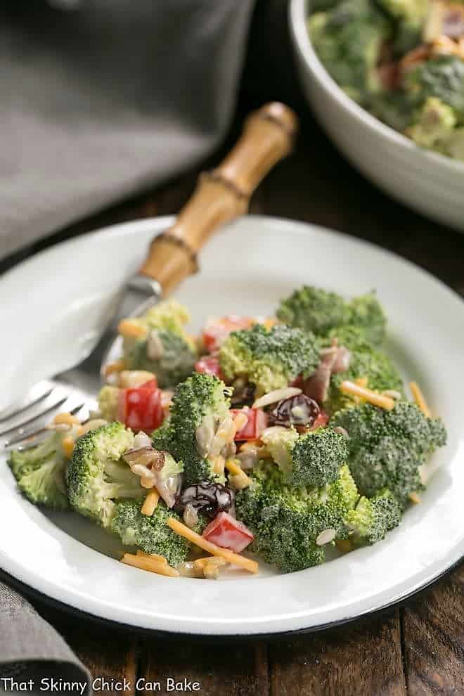 Broccoli Salad with Bacon and Dried Cherries on a white plate with a bamboo handled fork.