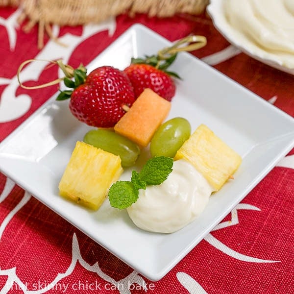 Fruit Kebabs with White Chocolate Mascarpone Dip on a small square plate with a dollop of dip and a sprig of mint.