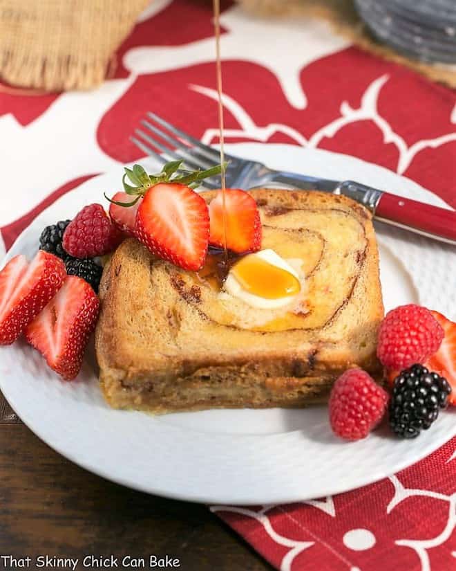 Overnight Cinnamon Bread French Toast with a drizzle of maple syrup on a white plate.