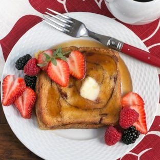 Overnight Cinnamon Bread French Toast on a white plate topped with berries