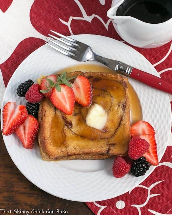  Overnight Cinnamon Bread French Toast on a white plate topped with berries
