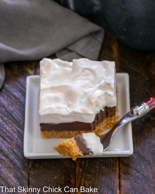 A s'mores bar on a white plate with a piece on a red handle fork.