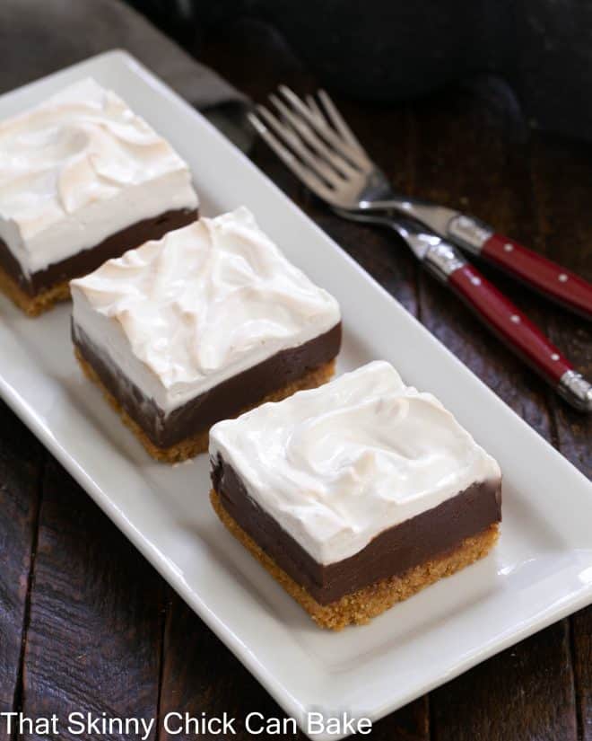 3 S'mores bars on a white ceramic tray with 2 forks