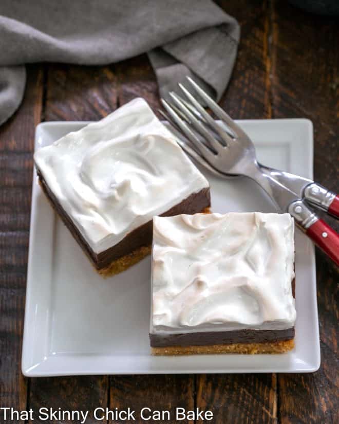2 s'mores fudge bars on a square white plate with 2 red handled forks
