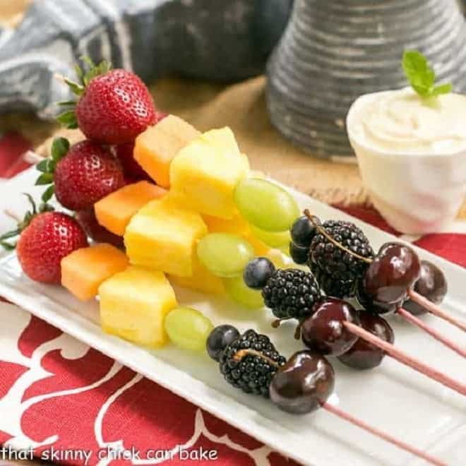 Rainbow fruit kabobs on a white ceramic tray